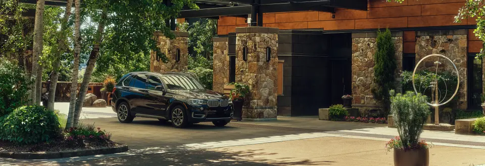 The Allison Inn & Spa entrance with stone and wood architecture, lush greenery, and a black SUV parked outside.