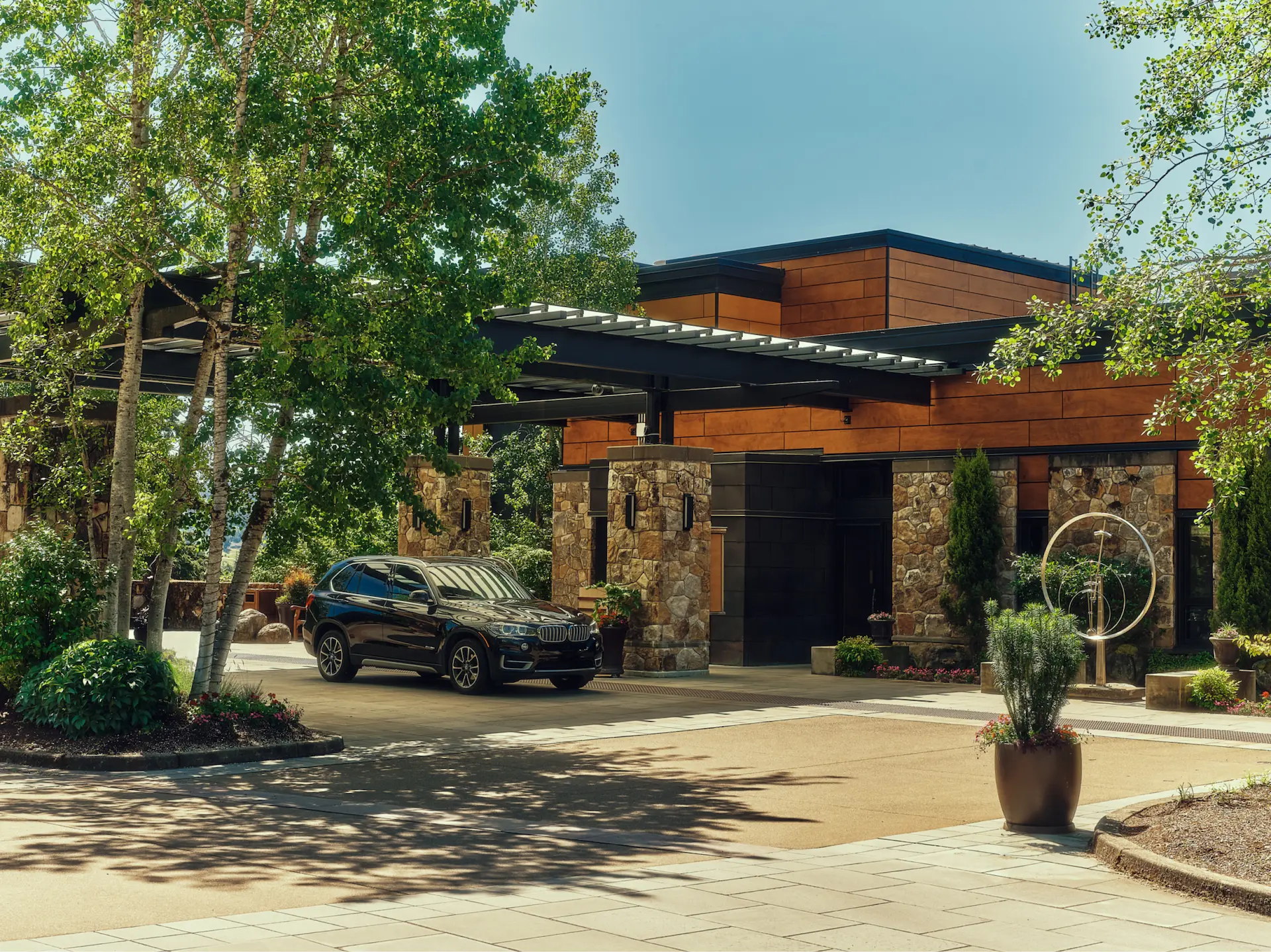 The Allison Inn & Spa entrance with stone and wood architecture, lush greenery, and a black SUV parked outside.