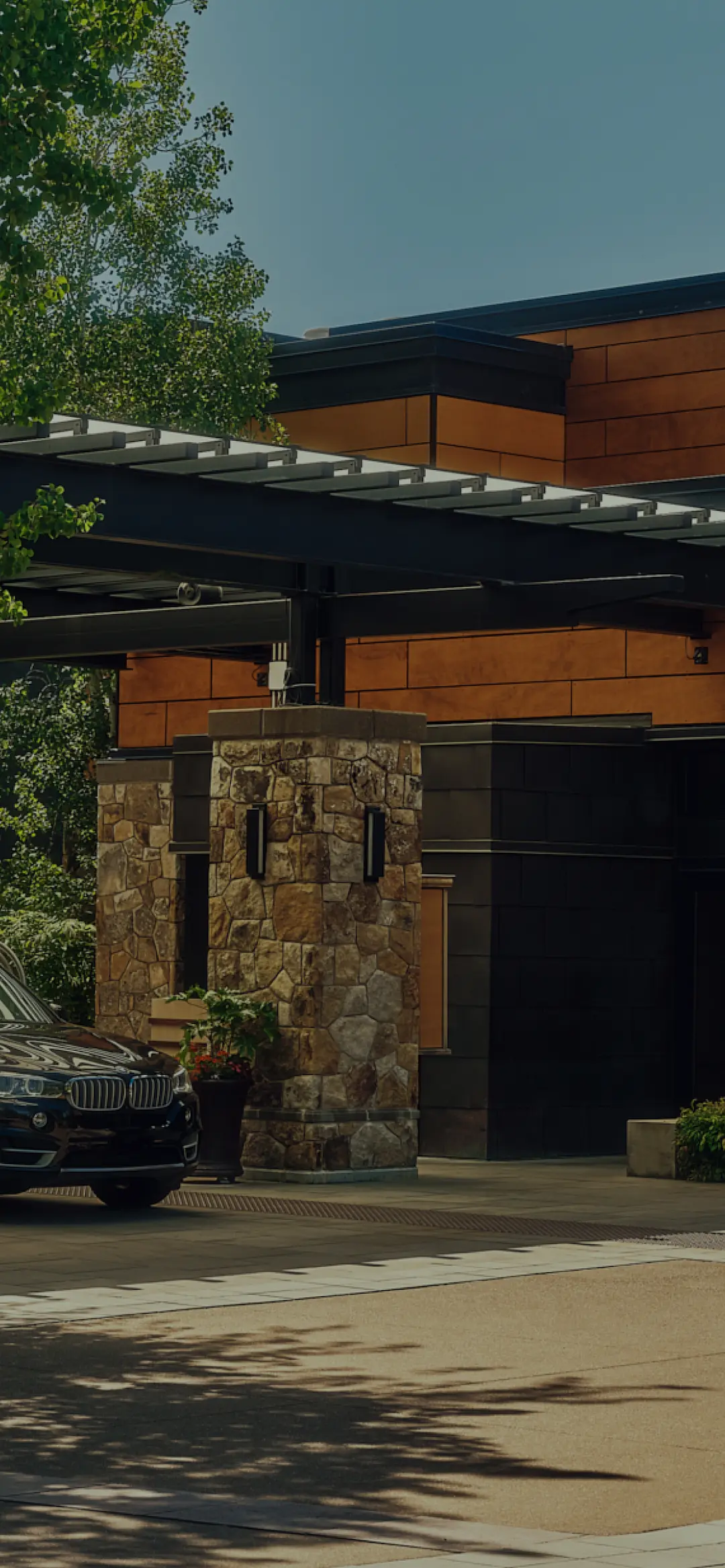 The Allison Inn & Spa entrance with stone and wood architecture, lush greenery, and a black SUV parked outside.