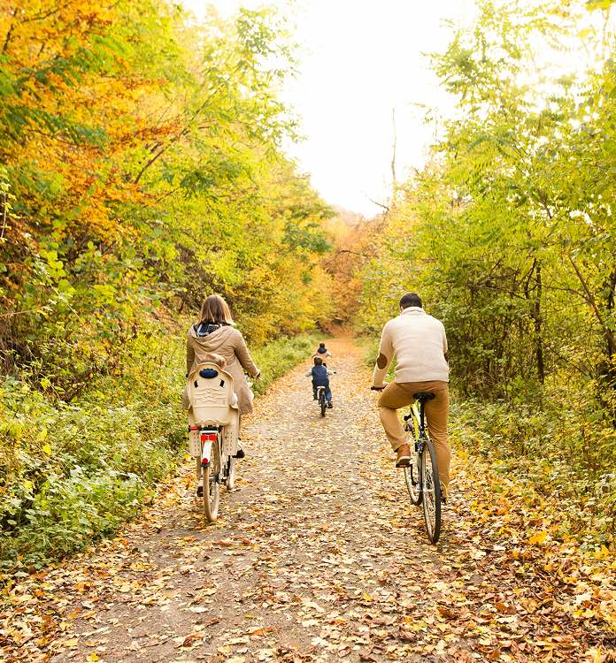Family biking along a trail surrounded by fall leaves
